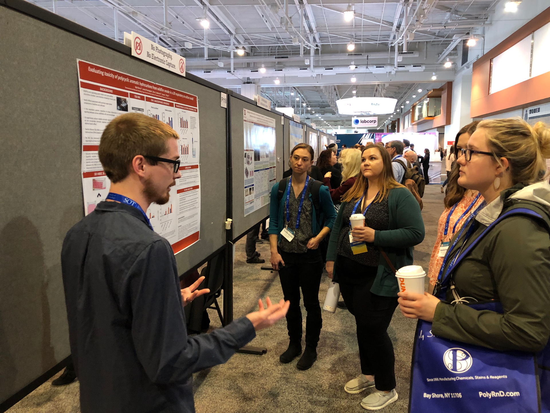 Presenter discussing wildfire smoke toxicity poster with a group of attendees